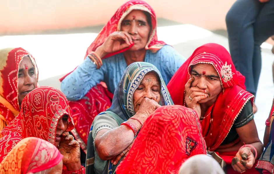 Elderly Indian women in colorful sarees sitting together, showcasing traditional Rajasthani attire and culture.