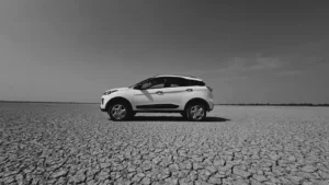 Side view of a white SUV parked on a dry, cracked, arid landscape in Rajasthan, India.