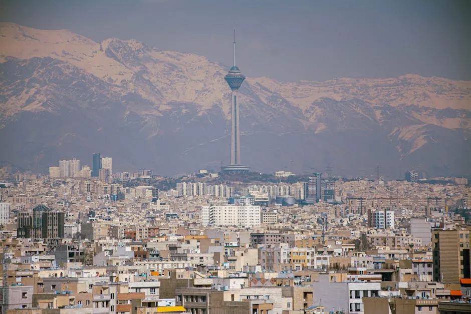 Aerial view of Tehran featuring Milad Tower against the Alborz Mountains.
