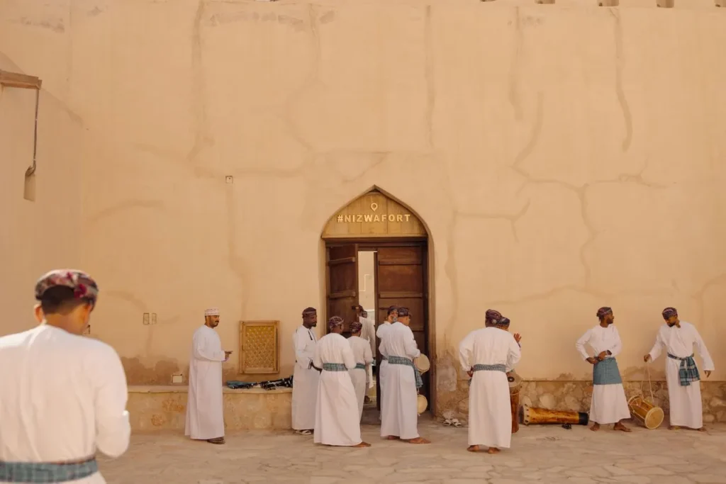 Group of men perform a traditional Omani dance in front of Nizwa Fort, Oman.