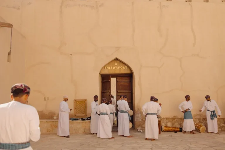 Group of men perform a traditional Omani dance in front of Nizwa Fort, Oman.