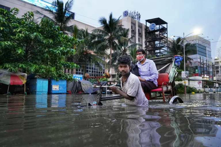 വെള്ളപ്പൊക്കത്തിൽ മുങ്ങിയ റോഡിൽ നിൽക്കുന്ന ആളുകൾ