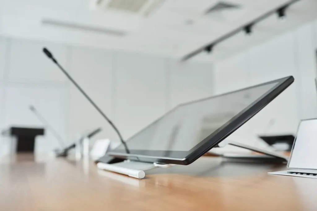 Close-up of a modern conference room with a digital screen and microphones.
